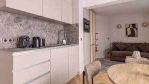 Une cuisine moderne dotée d’un plan de travail en granit, d’une cuisinière encastrée et d’un évier. On y trouve également un coin repas avec une table ronde et des chaises.