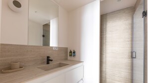 Un baño moderno con un espejo grande, un lavabo y una zona de ducha.