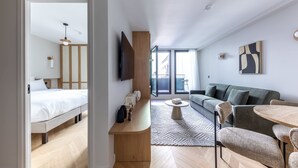 Una habitación de hotel moderna con cama, escritorio, sofá y mesa de comedor.