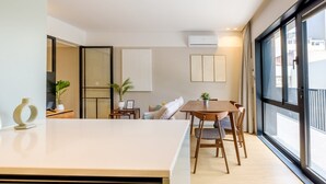 A modern apartment with a dining area, a sofa, and a large window.