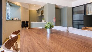 A modern living room with a wooden dining table, a sofa, and a TV.