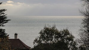 A coastal view with a house and trees in the foreground. - Tall Timbers (Ventnor)