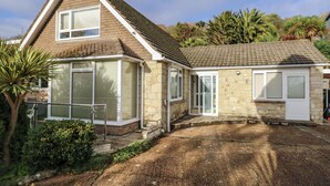 A two-story house with a stone facade, a tiled roof, and a front yard with a pathway leading to the entrance. - Tall Timbers (Ventnor)