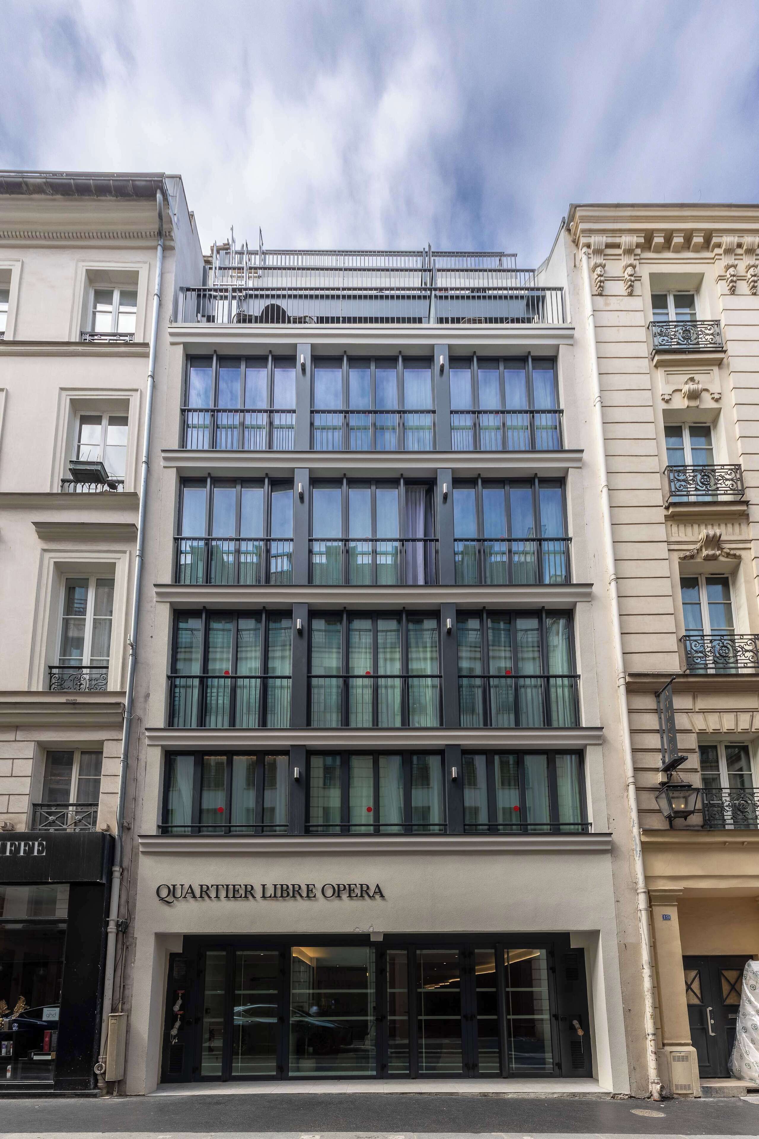 Un edificio con fachada moderna, varias ventanas y un cartel que dice 'QUARTIER LIBRE OPERA'.