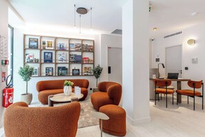 A modern living room with a sofa set, a coffee table, and a bookshelf filled with books and framed pictures.