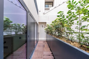 A narrow wooden pathway flanked by glass walls and a planter with greenery. - Opera -3 Bedroom / 2 living rooms connecting apt. (Paris)