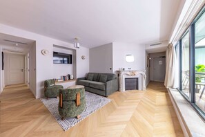 A modern living room with a sofa, two armchairs, a fireplace, and a large window. - Opera -3 Bedroom / 2 living rooms connecting apt. (Paris)