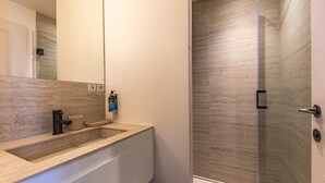 A modern bathroom with a large mirror, a sink, and a shower area.