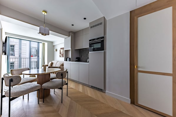 A modern kitchen with built-in appliances, a dining area with a round table and chairs, and a view of the outside. - Opera - One Bedroom in Paris (Paris)