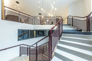 A multi-level interior with a staircase, metal railings, and hanging light fixtures. - Opera - One Bedroom Balcony (Paris)