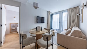 Ein modernes Wohnzimmer mit rundem Esstisch, Sofa und Wandfernseher.