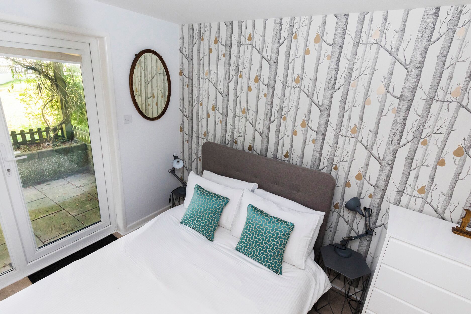 Een slaapkamer met een bed, nachtkastje, lamp en een kledingkast.