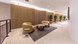 A modern lobby with a wooden slatted wall, a reception desk, comfortable seating, and potted plants. - Opera - Two Bedroom Balcony (Paris)