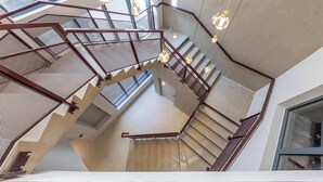 A modern interior with a staircase, metal railings, and hanging pendant lights. - Opera - Two Bedroom Balcony (Paris)