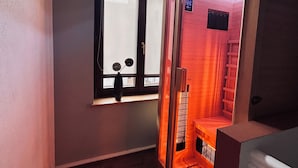 Un sauna avec une fenêtre, un banc en bois et un panneau indiquant qu’il s’agit d’un sauna.