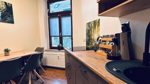 Une cuisine moderne avec des meubles en bois, un four encastré et une fenêtre donnant sur les arbres.