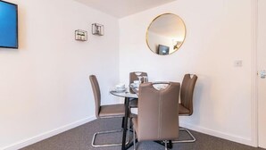 A small, modern room with a round mirror, a television, and a table with chairs.