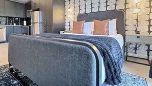 A modern bedroom with a large bed, a dark headboard, and a patterned wall.