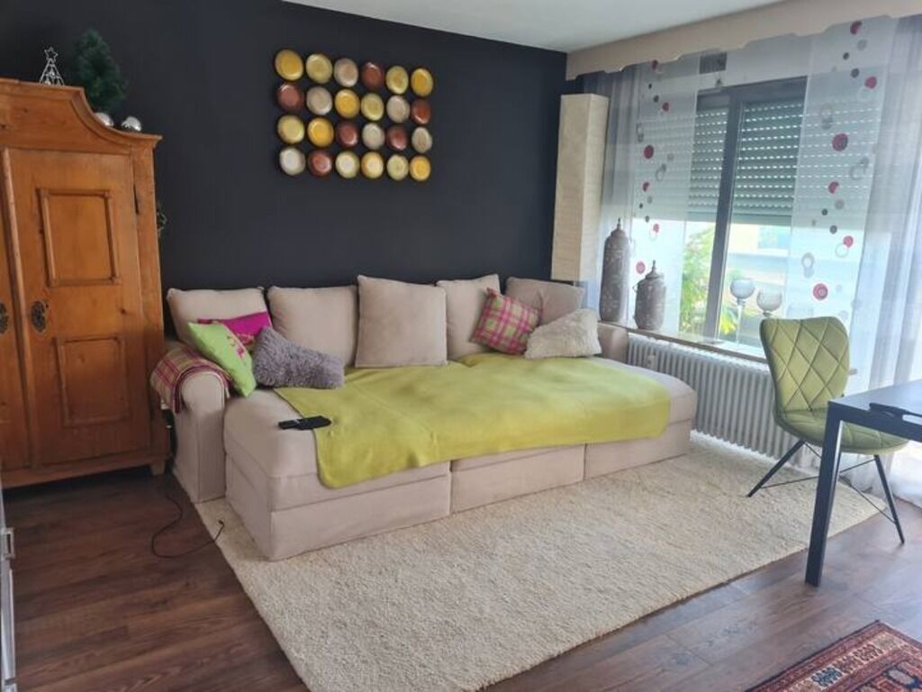 A cozy living room with a beige sofa, a yellow throw blanket, and a wooden cabinet.