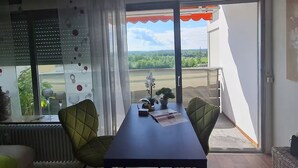 A dining area with a table, chairs, and a view of a green landscape through a large window. - Bad Füssing ... time out for two ...  (Bad Füssing)