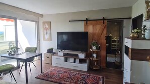 A modern living room with a flat-screen TV, a dining table, and a large rug. - Bad Füssing ... time out for two ...  (Bad Füssing)