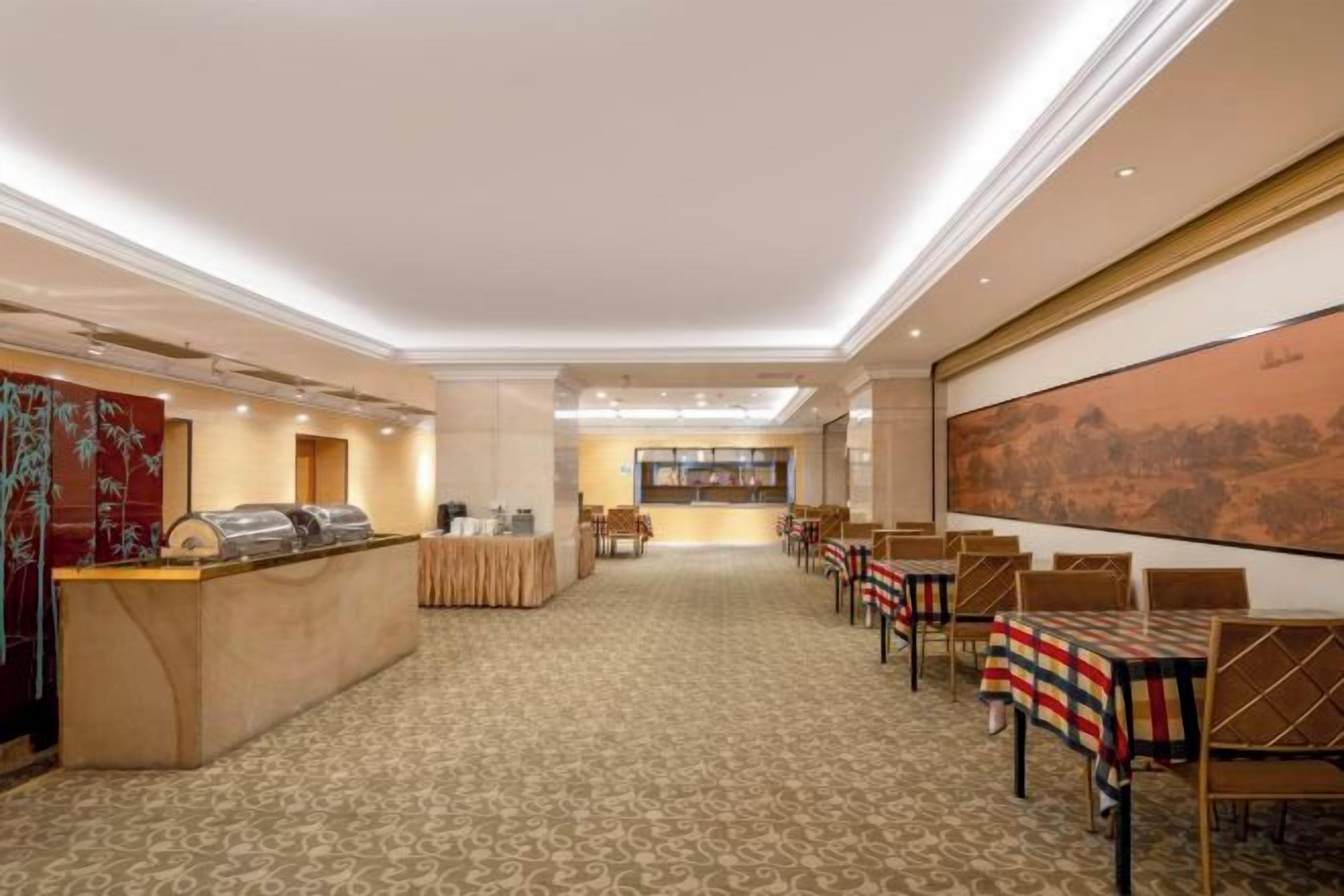 A hotel lobby with a reception desk, seating area, and a large painting on the wall.