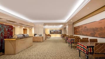 A hotel lobby with a reception desk, seating area, and a large painting on the wall.