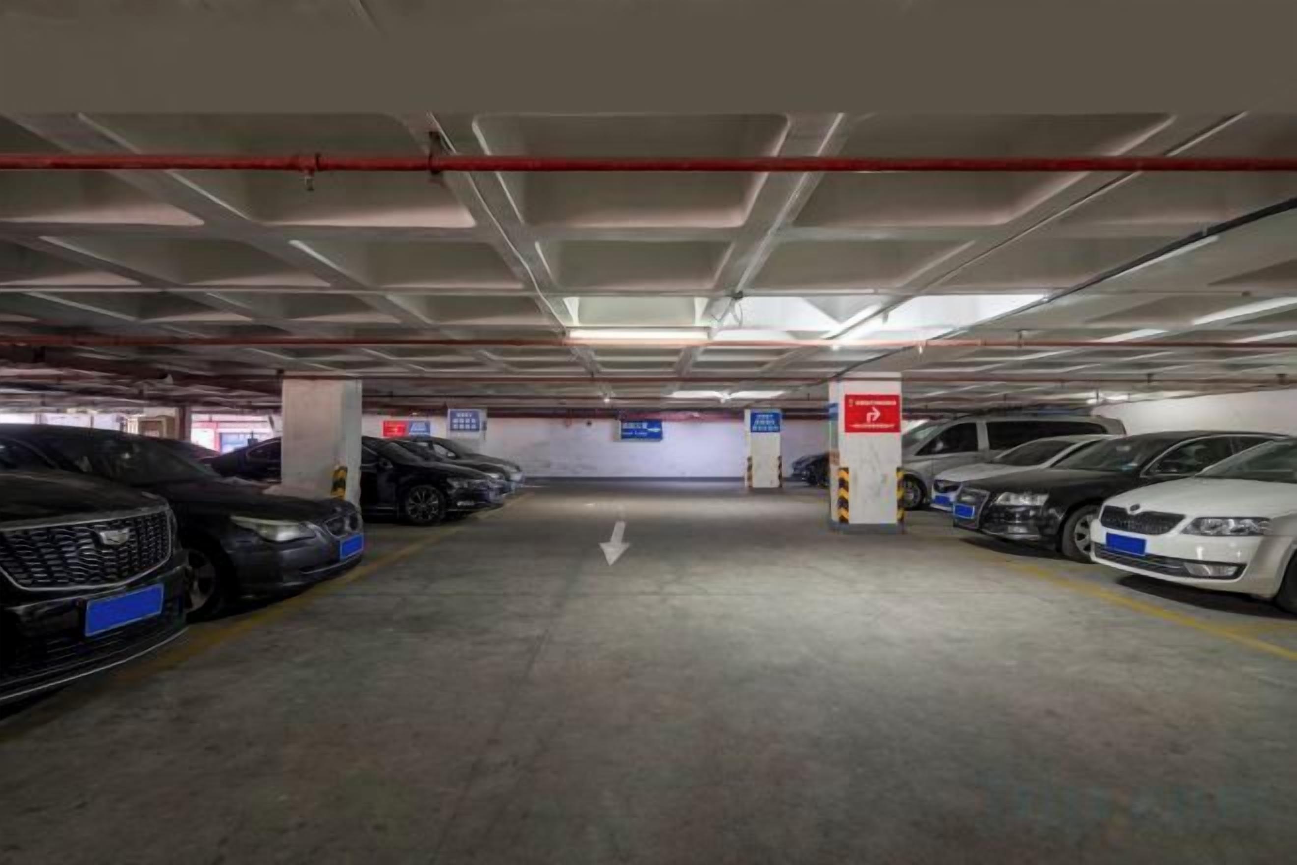 A multi-level parking garage with cars parked in designated spaces, clear directional signage, and a visible exit.