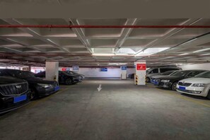 Een parkeergarage met meerdere verdiepingen, auto's geparkeerd op aangegeven plaatsen, duidelijke bewegwijzering en een zichtbare uitgang.
