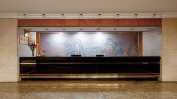 A reception area with a marble floor, a reception desk, and a wall-mounted artwork.