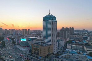 Un paisaje urbano con un edificio alto destacado, una intersección concurrida y estructuras urbanas circundantes.