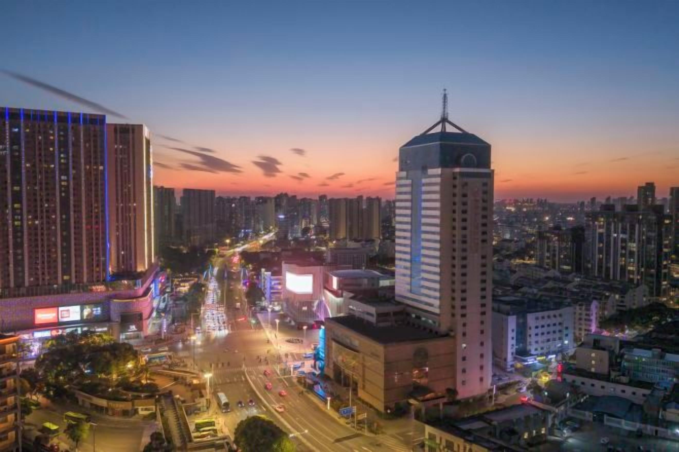 A cityscape at dusk with high-rise buildings, a busy street, and a prominent clock tower.