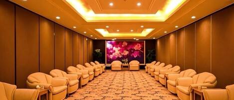 A conference room with rows of leather chairs, a patterned carpet, and a floral backdrop.