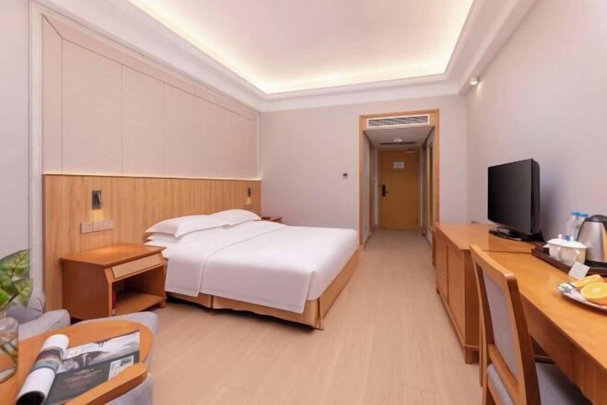 Una habitación de hotel con cama, mesita de noche, televisor y escritorio con silla.