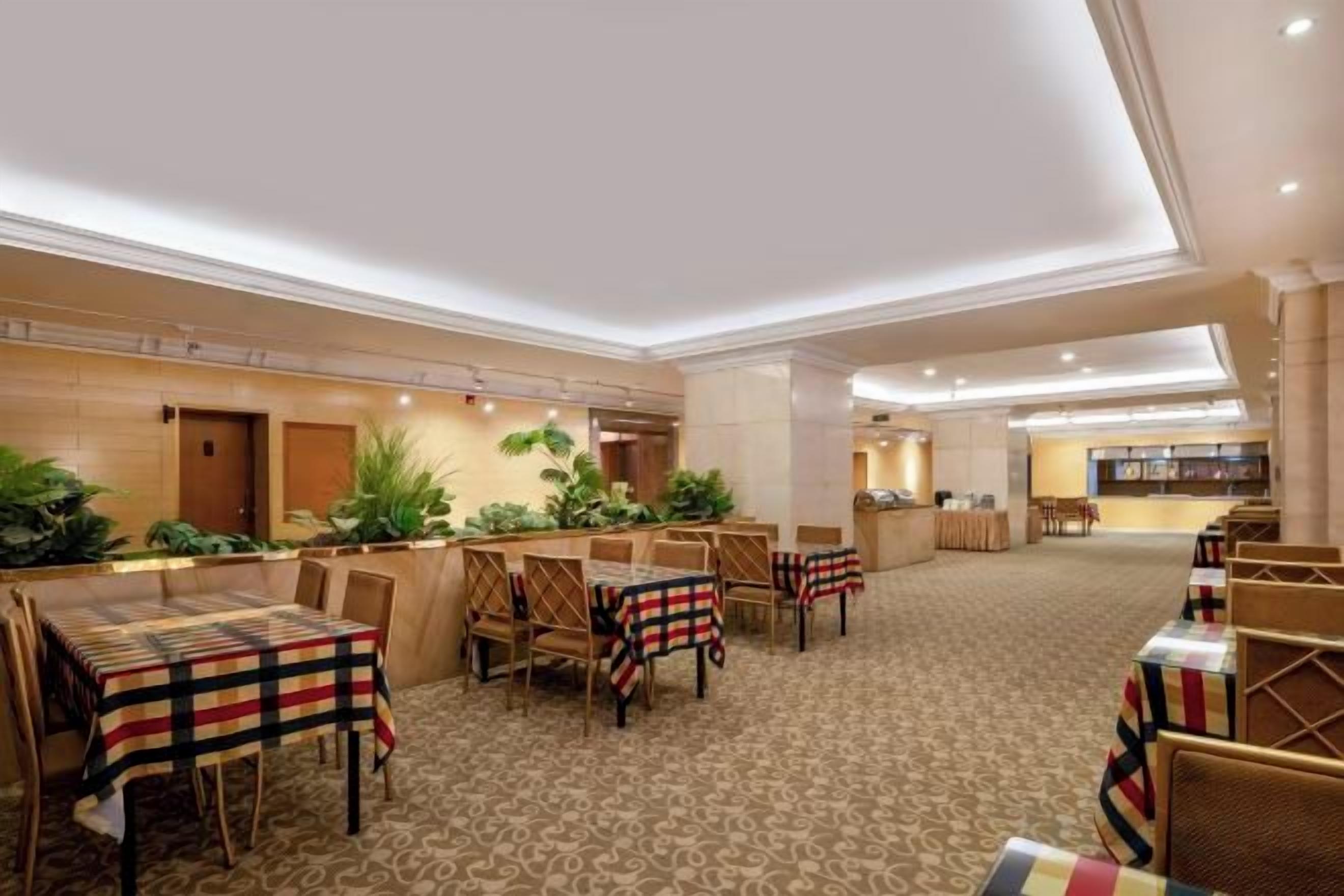 A hotel dining area with tables and chairs, a reception desk, and a bar area.
