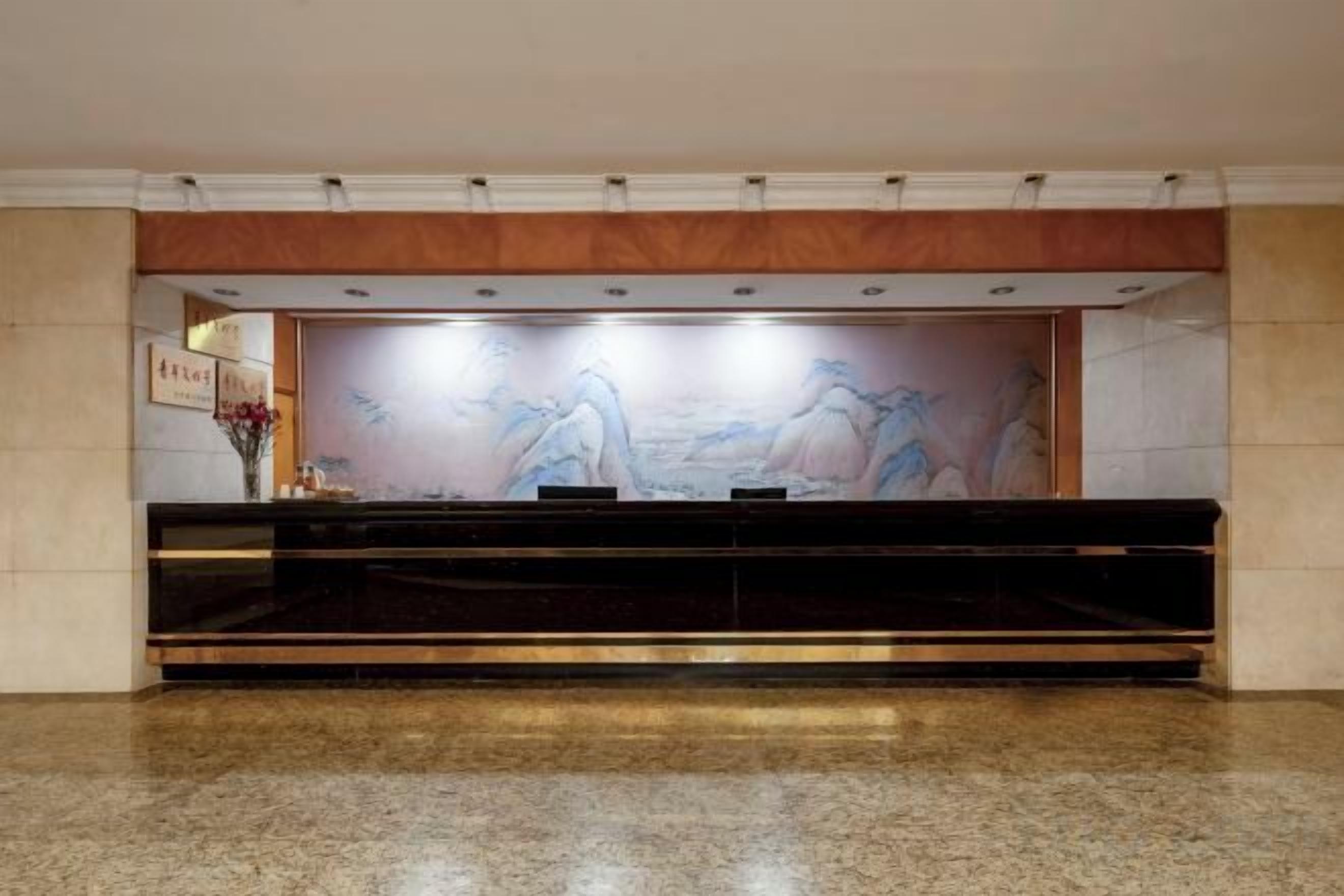 A reception area with a marble floor, a reception desk, and a wall mural.