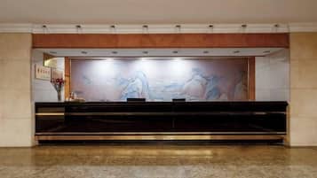 A reception area with a marble floor, a reception desk, and a wall mural.