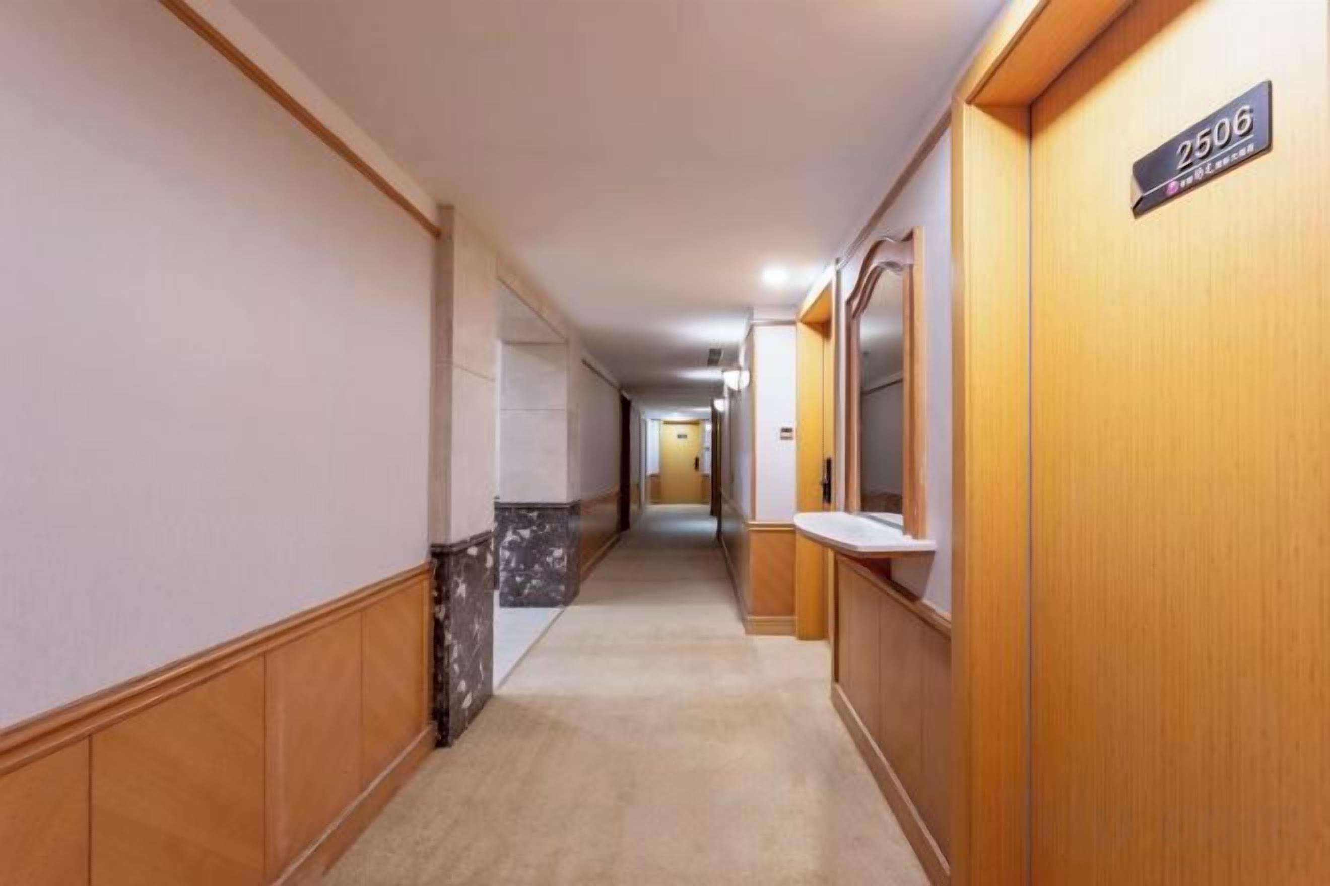 A hotel corridor with wooden paneling, a marble wall, and a sign indicating room number 2606.
