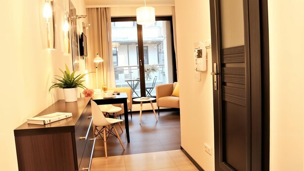 Habitación de hotel moderna con un escritorio de madera, una pequeña mesa de comedor, un sofá y un balcón con vistas a la ciudad.