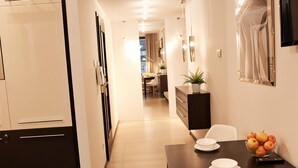 Una cocina moderna con comedor, que incluye una mesa de madera oscura, platos blancos y un bol de fruta.
