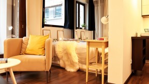 Una habitación de hotel moderna con sofá, cama, escritorio y espejo.