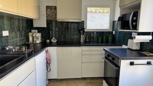 A compact kitchen with a microwave, toaster, and a window with a view.