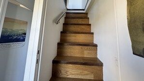 A wooden staircase with a handrail, white walls, and a poster on the left.