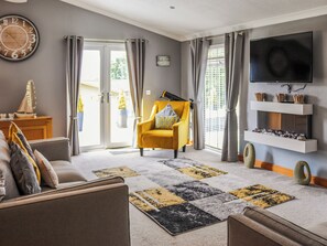 Un salon comprenant un canapé, un fauteuil et un téléviseur à écran plat fixé au mur.