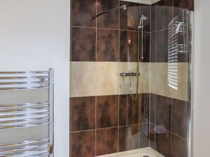 Une salle de bain moderne avec une douche à parois de verre, un porte-serviettes chromé et un mur recouvert de carreaux dans des tons de marron et de beige.