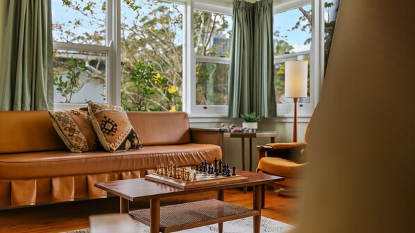 A cozy living room with a brown leather sofa, a chessboard, and a lamp.