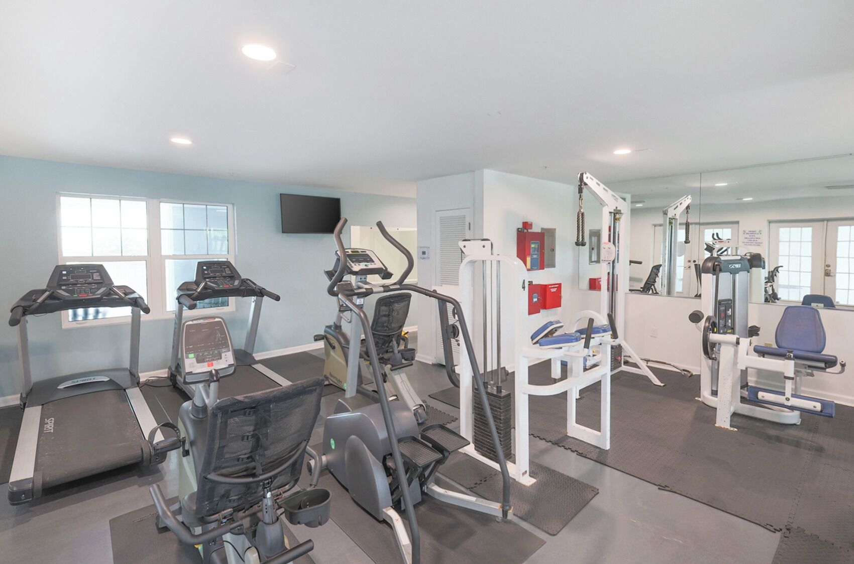 Un gimnasio con cintas de correr, elípticas y equipo de pesas.