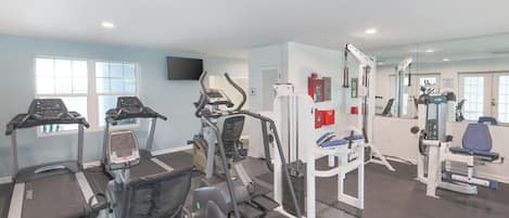 Un gimnasio con cintas de correr, elípticas y equipo de pesas.