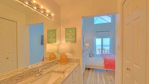 A bathroom with a large mirror, two wall-mounted lights, and a vanity with a marble countertop. - NEW! Beachside Bliss in Orange Beach (Orange Beach)