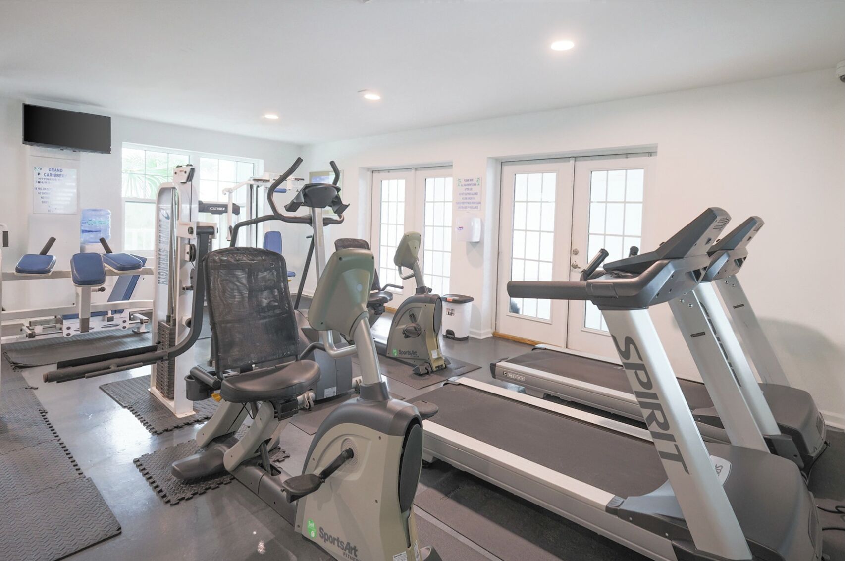 A gym with cardio machines, weight machines, and a mirrored wall.